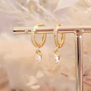 Boucles d’oreilles créoles dorées 3 microns en acier inoxydable, serties de zirconiums étincelants avec une goutte en pendentif. Élégantes, lumineuses et féminines, elles subliment le visage en douceur. Résistantes à l’eau et hypoallergéniques, Livraison offerte dés 69€.